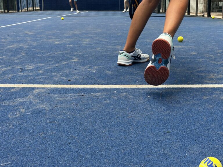 Chaussures de padel en appui sur un terrain sablé