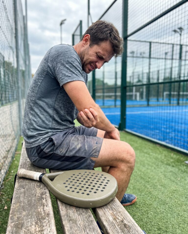 Joueur de padel se tenant le coude sur un banc