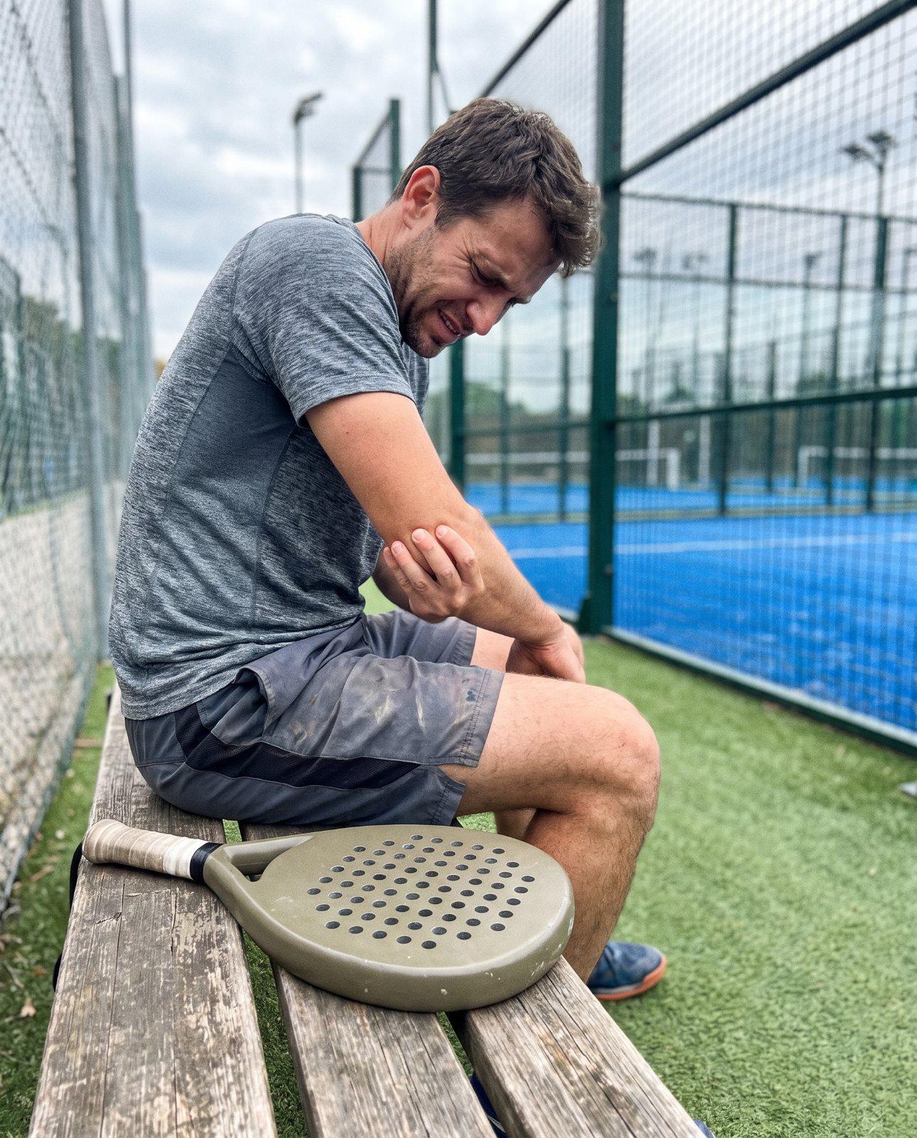 Joueur de padel se tenant le coude sur un banc