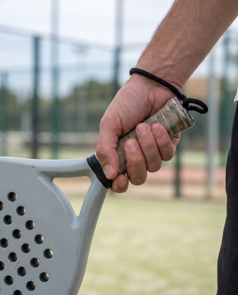 Main nue tenant le manche d'une raquette de padel