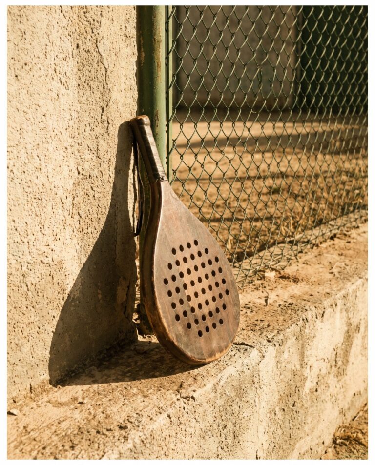 Ancienne raquette de padel en bois contre un mur